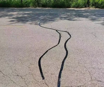 Repairing road cracks without using heated pavement joint strips
